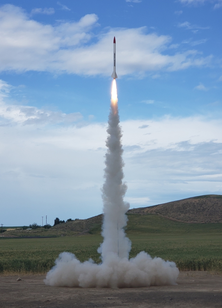 rocket launching into the blue sky, with fire and smoke below
